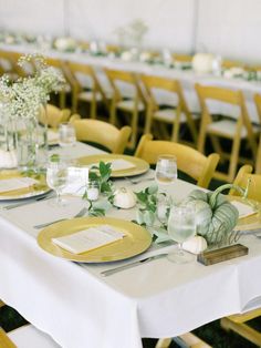 the tables are set with yellow plates and place settings for an elegant dinner or reception