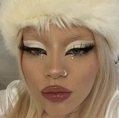 a woman with long blonde hair and white makeup wearing a fake fur hat on top of her head