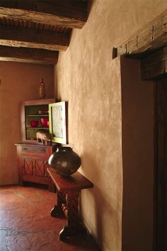 a large vase sitting on top of a wooden table next to a wall in a room