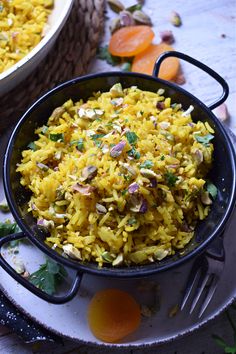 a bowl filled with yellow rice next to another bowl full of carrots and other vegetables