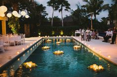 an outdoor wedding with candles floating in the water