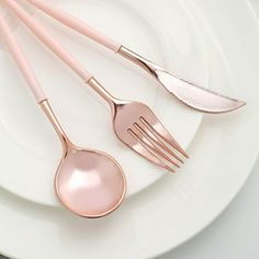 three pink utensils sitting on top of a white plate next to each other