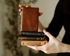 the woman is holding two books in her hands and one has a leather cover on it