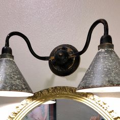 an old fashioned light fixture with two lights on it and a mirror hanging from the wall