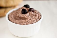 a white bowl filled with chocolate hummus and black olives