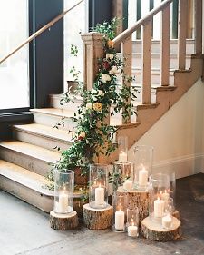 candles and flowers are arranged on wooden logs in front of the stairs at this wedding venue