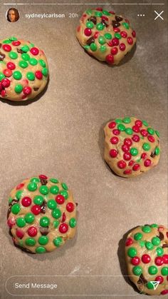 four cookies decorated with candy and sprinkles on top of a cookie sheet