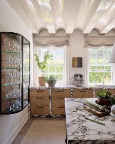 an elegant kitchen with marble counter tops and wooden cabinetry, along with glass shelves