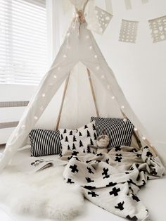 a teepee tent with lights and pillows on the floor