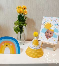 a baby's first birthday party with yellow flowers in a vase and an easel