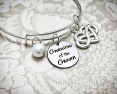 "♥ ✿ ♥ This elegant piece of jewelry will make a beautiful and sentimental gift that will best express your gratitude and love for your grandma. ♥ ✿ ♥ ✿ This piece includes ✿ ♥ disc pendant 20mm engraved with the words \"Grandma of the Groom\" ♥ infinity heart charm that symbolizes \"I love you forever\" ♥ authentic shell pearl (8mm) ♥ adjustable bangle 60mm in size (expandable to fit wrist 7-8\") ✿ Optional necklace (18-inch) OR keychain ✿ Leave a clear instruction at note to seller if you want Customizable Silver Charm Bracelet For Wedding, Silver Wedding Charm Bracelet, Silver Charm Bracelet For Wedding And Mother's Day, Mother's Day Wedding Gift Bracelet Jewelry, Groom Jewelry, Nana Jewelry, Grandma Bracelet, Grandmas Jewelry, Bride Bracelet