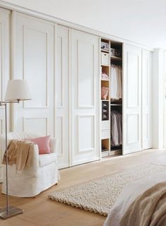 a bedroom with white closets and a bed in the corner next to a chair