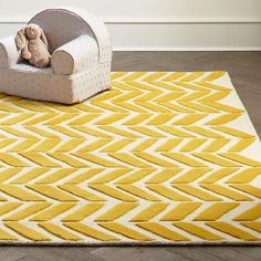 a yellow rug with a teddy bear sitting on it in front of a white chair