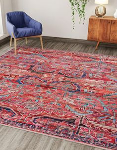 a red rug with blue and pink designs on the floor next to a blue chair