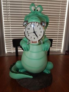 a green frog clock sitting on top of a wooden table