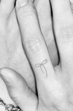 two hands holding each other with the word love tattooed on their thumbnails and fingers