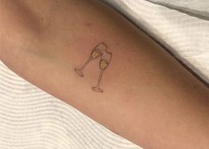 a woman's arm with a tattoo on it that has a glass of wine in it