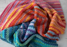 multicolored crocheted blanket laying on top of each other