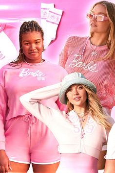 three women in matching pink outfits and one is wearing a white hat with the word barbie written on it