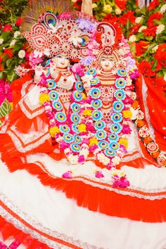 an elaborately decorated red and white costume on display in a flower filled area with flowers