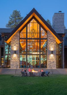 a house with a fire pit in the front yard and large windows on each side