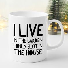 a white coffee mug with the words i live in the garden only sleep in the house