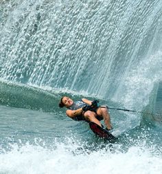 a man riding water skis on top of a body of water next to a waterfall