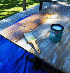 a paint can sitting on top of a wooden table next to a blue tarp