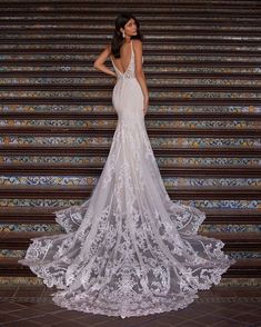 a woman in a wedding dress standing on some steps with her back to the camera