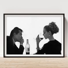 a black and white photo of two people drinking wine