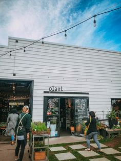 two people are walking towards the plant shop