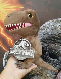 a hand holding a stuffed toy dinosaur with its mouth open