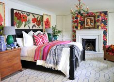 a bedroom with a bed, dressers and paintings on the wall above it's fireplace