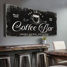 a coffee bar sign hanging on the wall above a table with chairs and stools