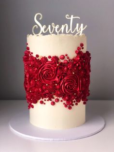 a white cake with red flowers and the word seventy on top