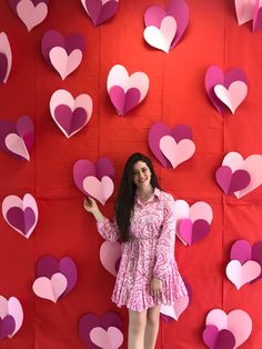 a woman standing in front of a wall with hearts on it