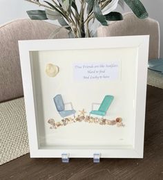 a white frame with two blue chairs and shells on the floor next to a potted plant