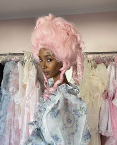 a woman with pink hair standing in front of dresses