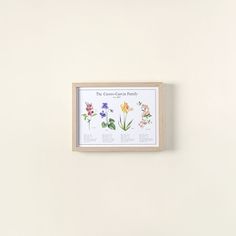 a white wall with some flowers on it and a framed poster hanging up against the wall