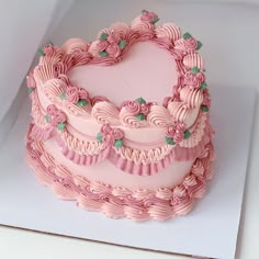 a heart shaped cake with pink frosting on top