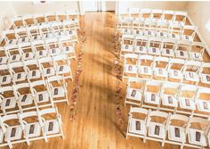 rows of white folding chairs sitting on top of a wooden floor