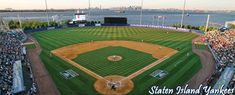 an aerial view of a baseball field with the water in the background and people watching