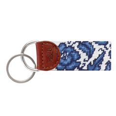 a keychain with a blue and white pattern on the front, featuring an oval leather