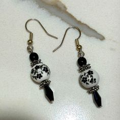 Stunning Handmade Dainty White Earrings Feature A Black Floral Design In These One Of A Kind Dangle Earrings. Accented With A Tiny Black Bead And Silvertone Spacers. Fishhook Style Lightweight Designed And Handcrafted By Me, Avant Designs Elegant Gift Idea For Birthdays, Anniversaries, And Holidays. An Artisan Designed Present They Won’t Find Anywhere Else. Traditional, Classic, Boho, Gypsy, Eclectic, Drop Earrings, Flower Earrings Black Dangle Earrings, Black Earrings Dangle, Jewelry Making Earrings, Coin Earrings, Making Earrings, Earrings Flower, Artisan Design, White Earrings, White Beads