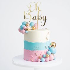 a cake decorated with gold, blue and pink icing that says oh baby on top