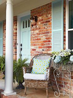 a chair sitting on top of a porch next to a planter filled with flowers