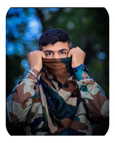 a man in camouflage is covering his face with a scarf and looking at the camera