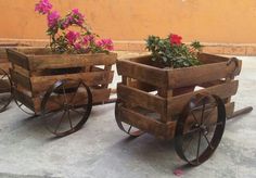 three wooden wagons with flowers in them sitting on the ground next to a wall