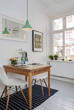 a dining room table with two chairs and a rug on the floor in front of it