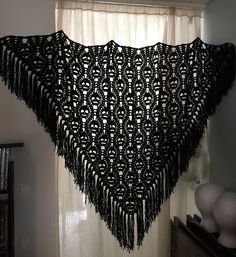 a black crocheted shawl hanging from a window